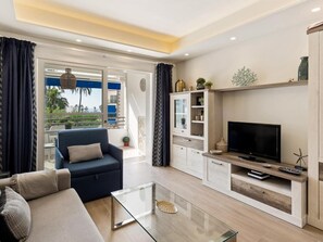 Ein modernes Wohnzimmer mit Sofa, Fernseher, Glastisch und integrierten Regalen.