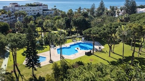 Um resort com uma piscina grande cercada por vegetação exuberante e vista para o mar.
