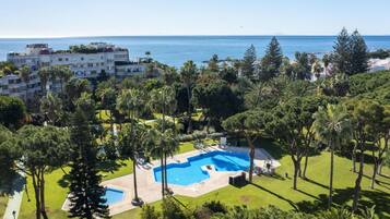 Un resort con una amplia piscina rodeada de exuberante vegetación y vistas al mar.