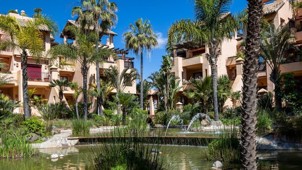 A resort with multiple-story buildings, palm trees, and a central water feature. - Apto Bah a de Alc Ntara San Pedro (Marbella)