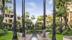 A resort with palm trees, a central water feature, and buildings with balconies. - Apto Bah a de Alc Ntara San Pedro (Marbella)
