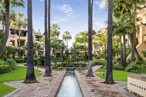 A resort with palm trees, a central water feature, and buildings with balconies. - Apto Bah a de Alc Ntara San Pedro (Marbella)