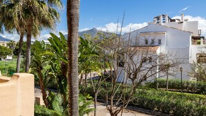 A residential area with a white building, palm trees, and a mountain in the background. - Apto Bah a de Alc Ntara San Pedro (Marbella)