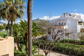 A residential area with a white building, palm trees, and a mountain in the background. - Apto Bah a de Alc Ntara San Pedro (Marbella)