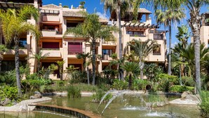 A multi-story hotel with a pool area featuring a small waterfall. - Apto Bah a de Alc Ntara San Pedro (Marbella)