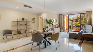 A modern living room with a dining area, a sofa set, and a balcony with a view. - Apto Bah a de Alc Ntara San Pedro (Marbella)
