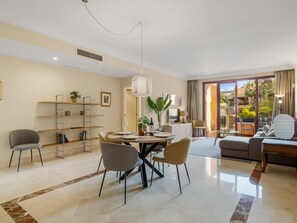 A modern living room with a dining area, a sofa set, and a balcony with a view. - Apto Bah a de Alc Ntara San Pedro (Marbella)