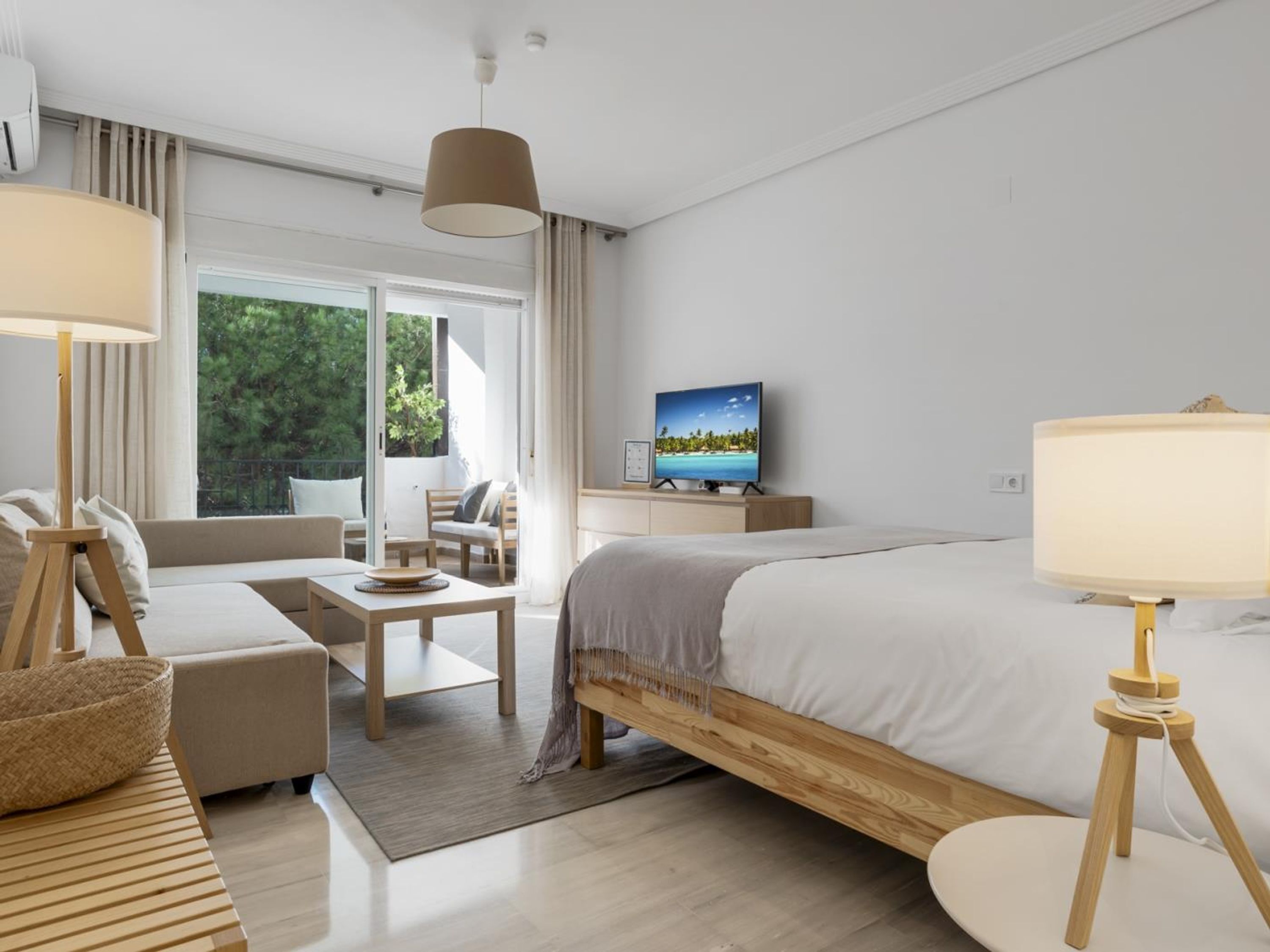 Una habitación de hotel moderna con cama, sofá, escritorio y televisor.