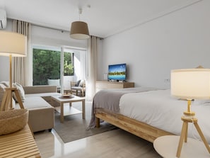 A modern hotel room with a bed, a sofa, a desk, and a television. - Confortable Estudio en Medina Garden ref 332 (Marbella)