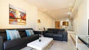 A modern living room with two black leather sofas, a white coffee table, and a painting on the wall. - Mimosas de Ban s (Marbella)