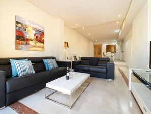 Ein modernes Wohnzimmer mit zwei schwarzen Ledersofas, einem weißen Couchtisch und einem Gemälde an der Wand.