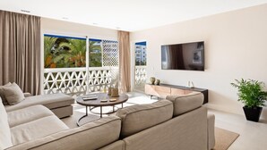 A modern living room with a sofa, a coffee table, and a TV mounted on the wall. - 2 Dormitorios Playas del Duque Ref 228 (Marbella)