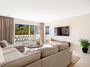 Ein modernes Wohnzimmer mit einer Couch, einem Couchtisch und einem an der Wand befestigten Fernseher.
