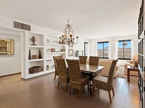 A dining area with a chandelier, wicker chairs, and a white interior. - OPQ Central Ban s (Marbella)