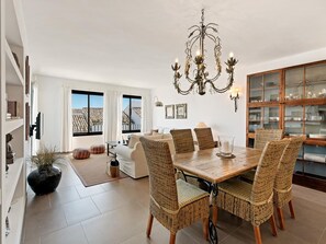 A spacious living area with a dining table, wicker chairs, a chandelier, and a view of the outside. - OPQ Central Ban s (Marbella)