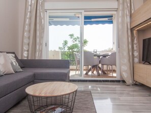 Ein modernes Wohnzimmer mit einem grauen Sofa, einem runden Couchtisch und einem Fernseher auf einer Holzkommode.