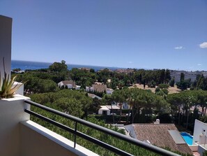 A residential area with a view of the sea, surrounded by greenery and buildings. - Estudio en Medina Garden Ref 362 (Marbella)