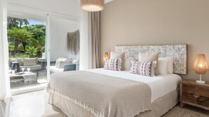 A bedroom with a large bed, a wooden nightstand, a hanging light fixture, and a view of a balcony with outdoor furniture. - Fant Stico Apartamento en Jardines de Ventura (Marbella)