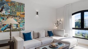 Una sala de estar moderna con un sofá, una mesa de centro, una lámpara y un cuadro grande en la pared.