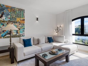 Ein modernes Wohnzimmer mit einer Couch, einem Couchtisch, einer Lampe und einem großen Gemälde an der Wand.