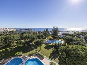 Ein Resort mit mehreren Schwimmbecken, üppiger Vegetation und Blick aufs Meer.