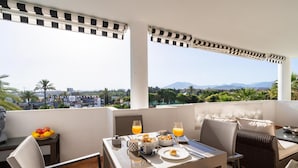 A balcony with a table set for breakfast, including fruits, bread, and orange juice. - Apartamento en Playa Roc o (Marbella)