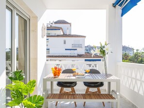 Ein Balkon mit einem Tisch für zwei Personen, ausgestattet mit einer Obstschale, Gläsern und einem Teller.