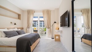 Ein modernes Schlafzimmer mit Bett, Fernseher und einem Balkon mit Blick auf Gebäude.