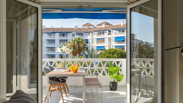 Ein Balkon mit Esstisch, Stühlen und einem Blumentopf.