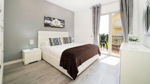 Quarto com cama, mesa de cabeceira e vista para o exterior.