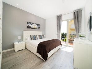 Ein Schlafzimmer mit Bett, Nachttisch und Blick ins Freie.