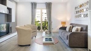 Uma sala de estar moderna com um sofá, poltronas, uma mesa de centro e uma televisão.