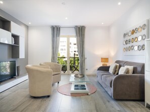Ein stilvolles Wohnzimmer mit einer Couch, Sesseln, einem Couchtisch und einem Fernseher.