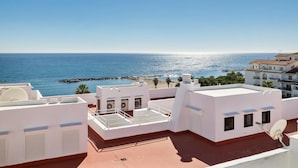 A rooftop terrace with a view of the sea and a rocky breakwater. - Casa C diz 607 Playas del Duque (Marbella)