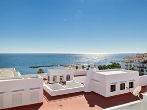 Eine Dachterrasse mit Blick auf das Meer und einen Felssteg.