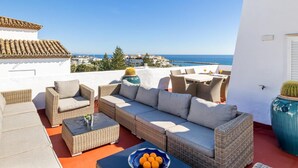 A rooftop terrace with wicker furniture, a table with oranges, and a view of the sea. - Casa C diz 607 Playas del Duque (Marbella)
