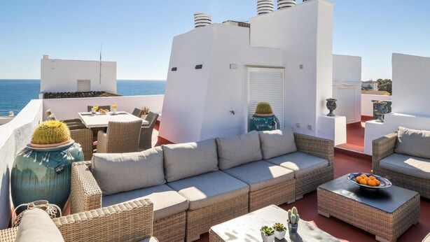 A rooftop terrace with a sofa set, a dining table, and a view of the sea. - Casa C diz 607 Playas del Duque (Marbella)