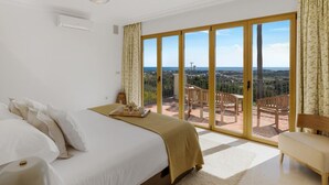 Ein Hotelzimmer mit einem großen Bett, einer Holzbank und einem Balkon mit Blick auf die Landschaft.