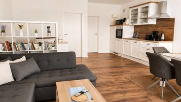 A modern living room with a grey sofa, a wooden coffee table, and a bookshelf filled with books and decorative items.