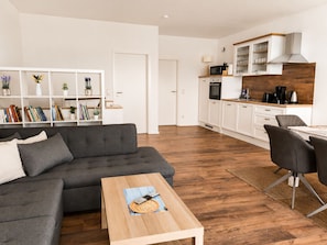 A modern living room with a grey sofa, a wooden coffee table, and a bookshelf filled with books and decorative items. - 120-square-meter vacation rental with lake views, dock right on the water / Sleeps 8, 3 bedrooms (Neukieritzsch)