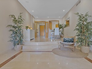 A spacious hallway with a dining area, a kitchen, and a seating area with a round rug. - Mimosas de Ban s 10 2 2 E (Marbella)