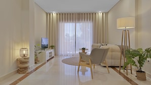 A modern living room with a sofa, a coffee table, and a TV. There are curtains, a floor lamp, and potted plants. - Mimosas de Ban s 10 2 2 E (Marbella)