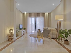 A modern living room with a sofa, a coffee table, and a TV. There are curtains, a floor lamp, and potted plants. - Mimosas de Ban s 10 2 2 E (Marbella)