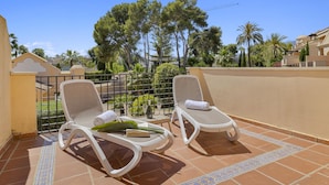 A terrace with two sun loungers, a tiled floor, and a view of trees and buildings. - Mimosas de Ban s 10 2 2 E (Marbella)
