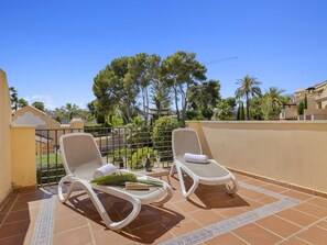 A terrace with two sun loungers, a tiled floor, and a view of trees and buildings. - Mimosas de Ban s 10 2 2 E (Marbella)