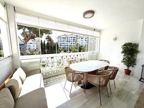 A balcony with a view of a building, a table with chairs, and a potted plant. - 2 Dormitorios Playas del Duque ref 229 (Marbella)