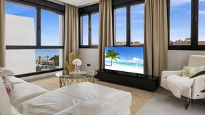 A modern living room with a flat-screen TV, white sofas, and large windows with curtains. - Tico con Vistas al mar (Marbella)