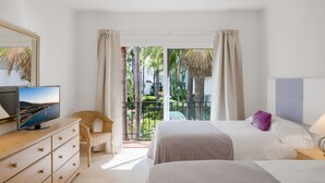 Ein Hotelzimmer mit Balkon, Fernseher, Bett mit Kissen und Kommode.