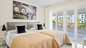 A hotel room with a bed, a painting, and a view of the outside. - Amplio Apartamento en Playas del Duque (Marbella)