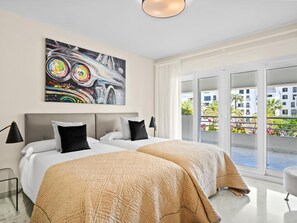 A hotel room with a bed, a painting, and a view of the outside. - Amplio Apartamento en Playas del Duque (Marbella)